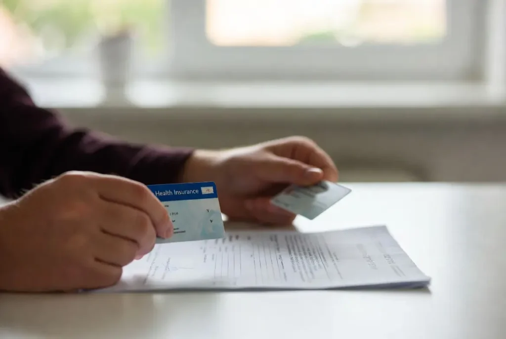 Mãos segurando cartão de plano de saúde e prescrição médica representando direito à cobertura