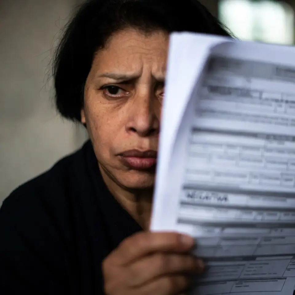 Paciente analisando documento de negativa de cobertura do Olaparibe pelo plano de saúde baseado no Rol da ANS.